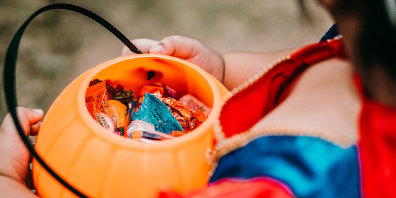 Little girl in costume holding trick or treat candy