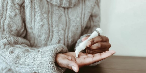 Close-up of woman pouring lotion into palm of hand