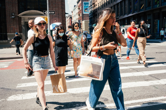 Image: Pedestrians carrying shopping bags cross a street in New York on Aug. 25, 2021.