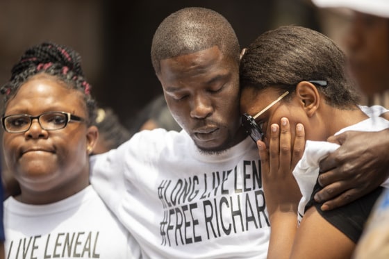 Image: Cheryl Frazier, sister of Leneal Frazier; Orlando Frazier, brother of Leneal; and Jamie Bradford, daughter of Leneal, embrace one another during a news conference outside of City Hall in Minneapolis on July 9, 2021.