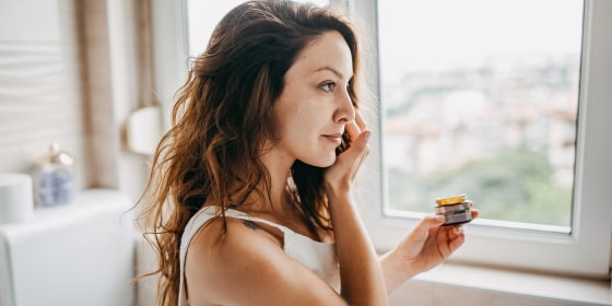 Young woman applies facial cream