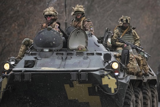 Image: Ukrainian soldiers sit atop armored personnel carriers driving on a road in the Donetsk region, eastern Ukraine on Feb. 24, 2022.