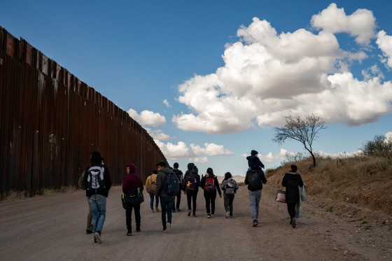 IMage: A group of migrant families from Central America walk near the border wall between the United States and Mexico near Sasabe, Ariz., on Jan. 23, 2022.