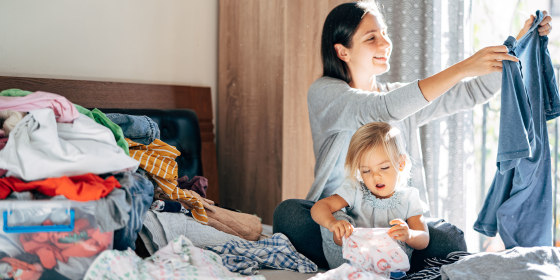 Smiling Mother And Daughter Folding Clothes At Home