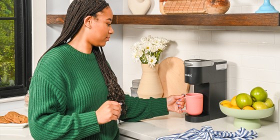 Woman holding cup under Keurig