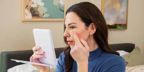 Woman touching her face while looking in her mirror