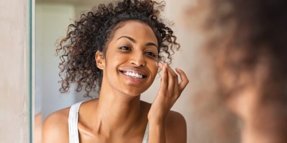 Black girl applying lotion on face