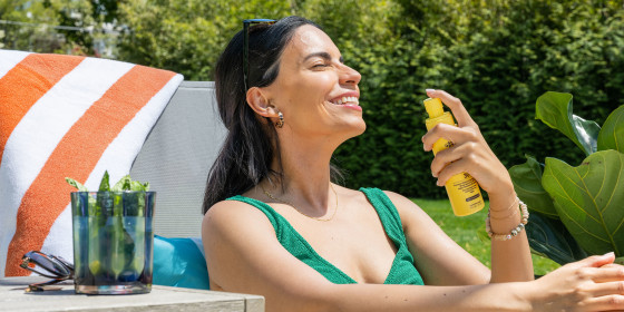 Woman spraying sunscreen on her face