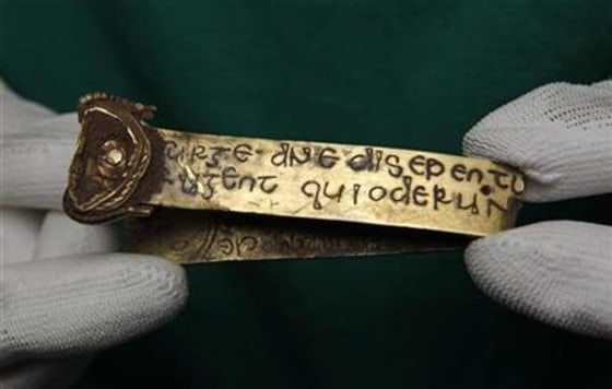 A strip of gold bearing a Biblical inscription is held by a member of museum staff in Birmingham, central England