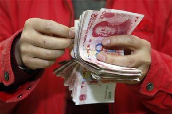 A customer counts yuan banknotes at a bank in Suining