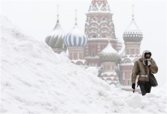 A woman walks in the Red Square under heavy snowfall with St.Basil's Cathedral in the background in central Moscow