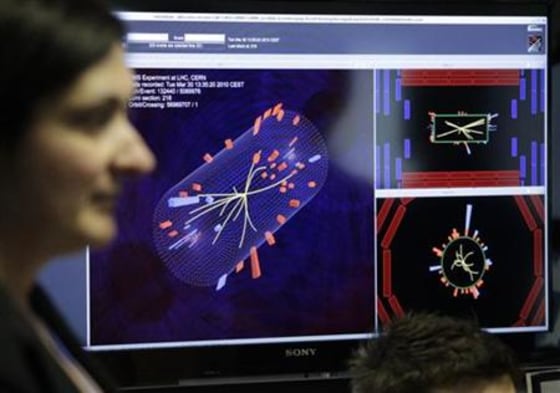 A scientist stands in front of pictures of the first successful collisions at full power at the CMS experience control room of the LHC at the CERN in Meyrin