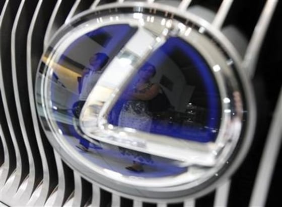 Visitors are reflected in a logo of a Toyota Motor's Lexus car at a showroom in Tokyo