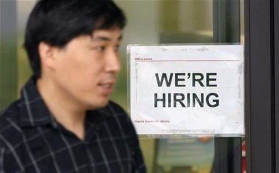 A man walks past a hiring sign at an Office Depot