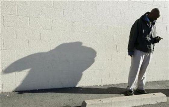 Pro Chrysler Jeep salesperson Barber checks his cell phone while waiting for customers at the Chrysler dealership in Thornton