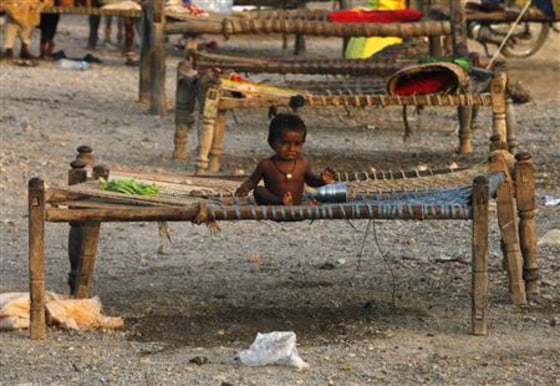 A boy sits on a bed in a makeshift roadside camp for flood victims, in Muzaffargarh district of Punjab province