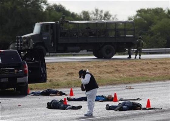 Forensic worker takes pictures at a crime scene where five hitmen were killed in a shootout with soldiers in the municipality of Juarez