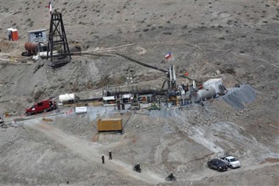Workers operate the Xtrata 950 drill, which is digging a hole for trapped miners to escape from, in Copiapo