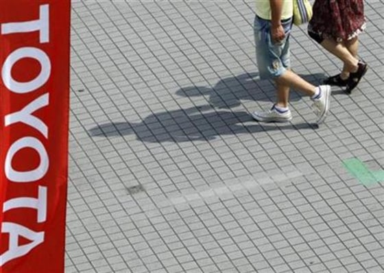 Passers-by walk past a Toyota Motor flag near the company's showroom in Tokyo