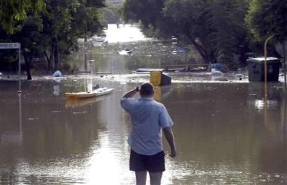 A man looks at debris floating across a flooded street in the inner Brisbane suburb of West End