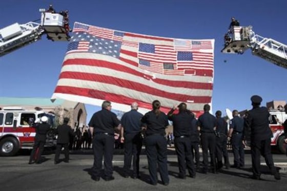 Firefighters raise an American flag recovered from Ground Zero after the September 11 attacks in New York City at St. Elizabeth Ann Seton Church at the funeral of 9-year-old Christina Green in Tucson, Arizona