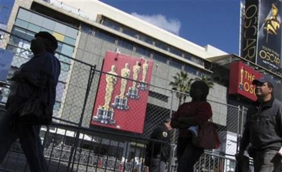 People walk along Hollywood Boulevard outside the Kodak Theatre as setup continues for the Oscars in Hollywood