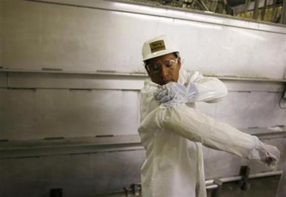 A worker fastens a plastic cover over a Kevlar sleeve made to protect his arms as he returns from a break at the West Liberty Food processing plant in West Liberty