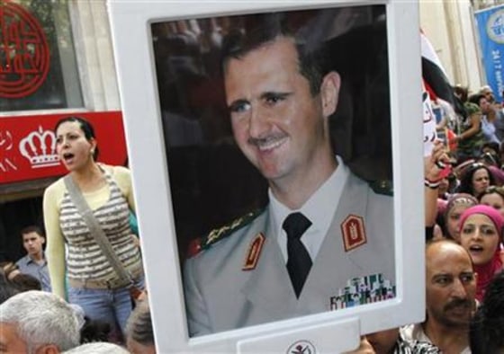 Supporters of Syrian President Bashar al-Assad's hold pictures of al-Assad during a rally at al-Sabaa Bahrat square in Damascus