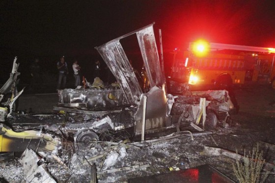 A fire truck stands near the burnt remains of a delivery truck on a road on the outskirts of Morelia