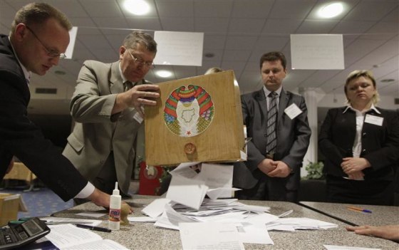 A member of local electoral commission empties ballot box at polling station after parliamentary election in Minsk
