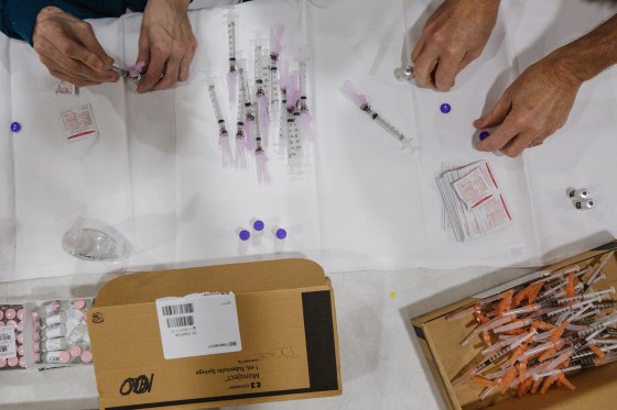 Image: Healthcare workers prepare doses of the Pfizer-BioNTech Covid-19 vaccine to administer to staff members of the Clarendon School District at Manning High School in Manning, S.C.,
