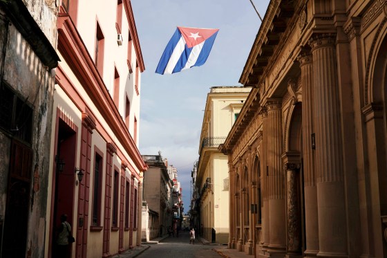 Image: A Cuban flag flies over a street in downtown Havana