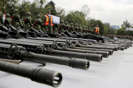 Mexican soldiers stand guard next to weapons seized from alleged drug traffickers or handed in by residents before they are destroyed at a military zone in Mexico City
