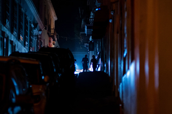 Image: People walk in a street left in darkness by a power outage following a cyber attack cyberattack in Old San Juan, Puerto Rico, on June 10, 2021.