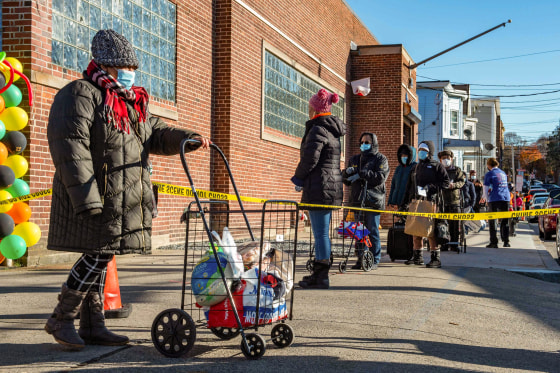 Image: A woman exits the pantry with a cart of food at the La Colaborativa Food Pantry in Chelsea, Mass., on Nov. 23, 2021.