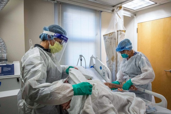 Image: A U.S. Marine veteran is treated by medical workers in a negative pressure room in the Covid-19 ward at the U.S. Department of Veterans Affairs Boston Healthcare system campus and medical center in West Roxbury, Mass. on Jan. 11, 2022.