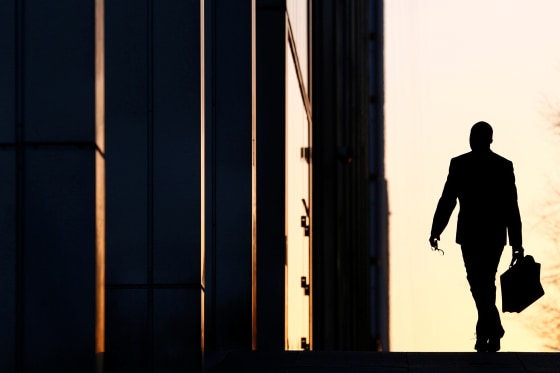 FILE PHOTO: A worker arrives at his office in the Canary Wharf business district in London