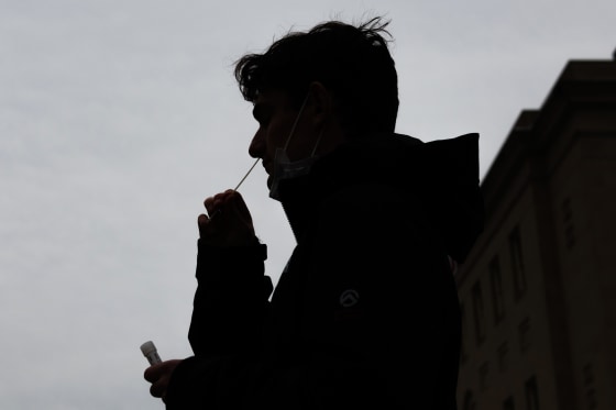 A person self-administers a Covid-19 PCR test while in line at a testing site in Washington on Jan. 5, 2022.