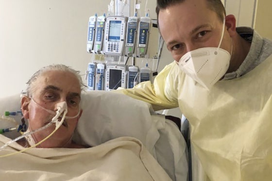 David Bennett Jr., right, stands next to his father's hospital bed in Baltimore on Jan. 12, five days after doctors transplanted a pig heart into Bennett in a last-ditch effort to save his life.