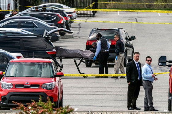 Officials load a body into a vehicle at the site of a mass shooting at a FedEx facility in Indianapolis, Indiana, on April 16, 2021.
