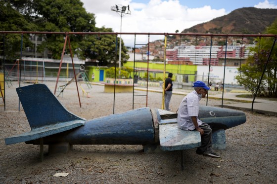 An elderly man sits on a plane made of cement at a park near a soup kitchen as he waits to pick up his free lunch in Caracas, Venezuela, on March 11, 2022.