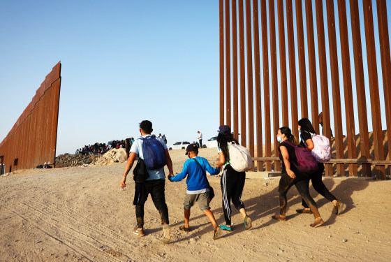 Immigrants cross through a gap in the U.S.-Mexico border
