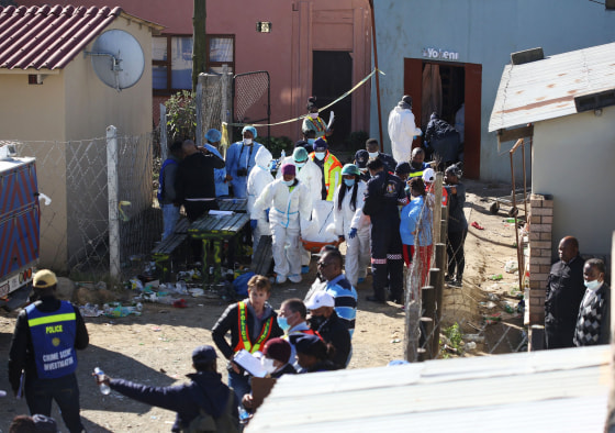 Forensic personnel carry a body out of a township pub in South Africa's southern city of East London on June 26, 2022.