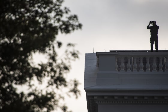 Image: A member of the Secret Service looks out from the roof of the White House on Sept 11, 2019.