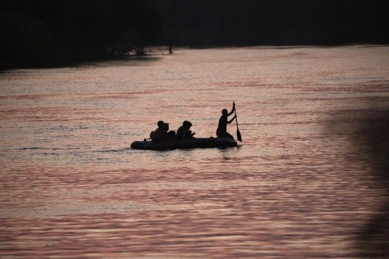 A smuggler paddles a small inflatable raft across the Rio Grande from Mexico into the U.S. carrying migrant families in Roma, Texas, on March 24, 2021.