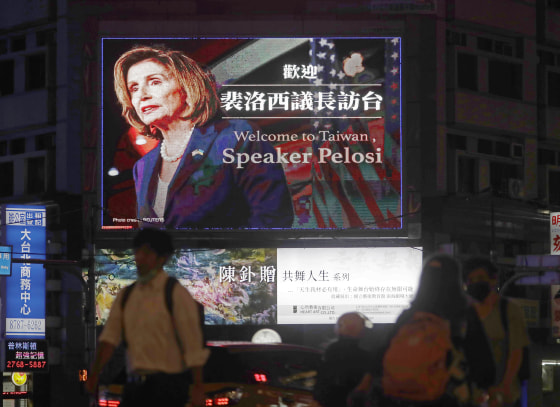 People walk past a billboard in Taipei, Taiwan welcoming House Speaker Nancy Pelosi