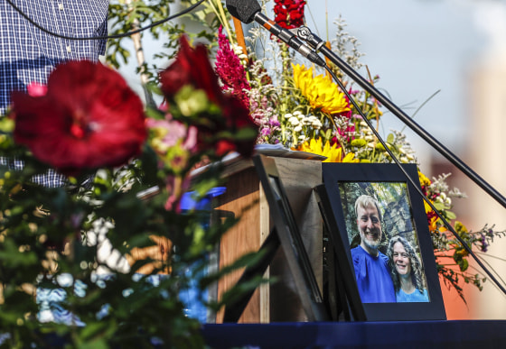 Image: A photo of Tyler and Sarah Schmidt sits on the podium during the Celebration of Life event for Tyler, Sarah, and Lula Schmidt held at Overman Park on Aug. 2 2022 in Cedar Falls, Iowa.