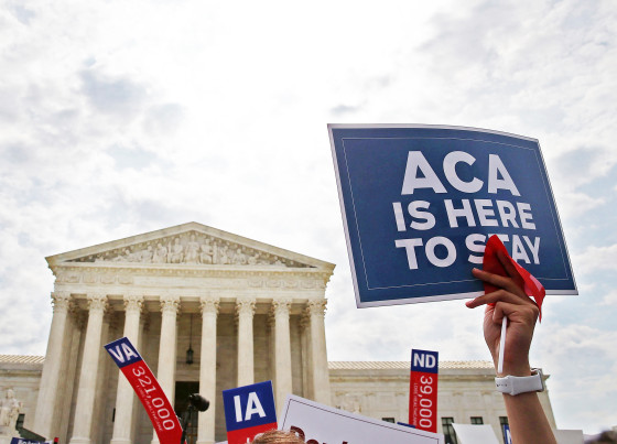 A person holds at sign that reads "ACA Is Here To Stay" at the Supreme Court