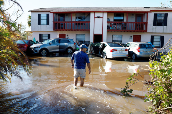 A man walks through flood waters to his apartment in Fort Myers