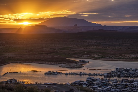 The sun rises behind Navajo Mountain and boats in Wahweap Bay at Lake Powell on Sept. 1, 2022 near Page, Ariz.